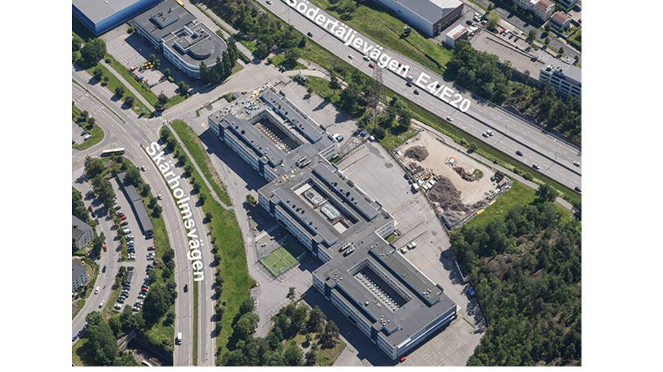 Flygfoto över ett område i Sätra mellan E4 Södertäljevägen  och Skärholmsvägen.  Skolbyggnaden i mitten av fotot.